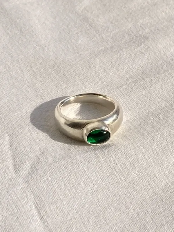 A silver ring set with a green stone in a closed bezel