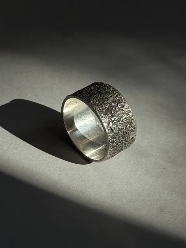 A wide silver band with a rough hammered texture