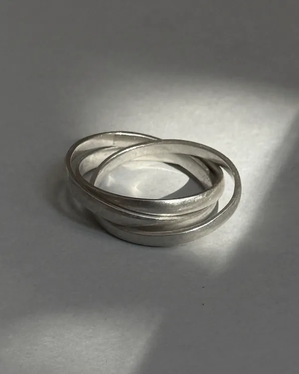 Two interlocking plain silver bands on a pale surface