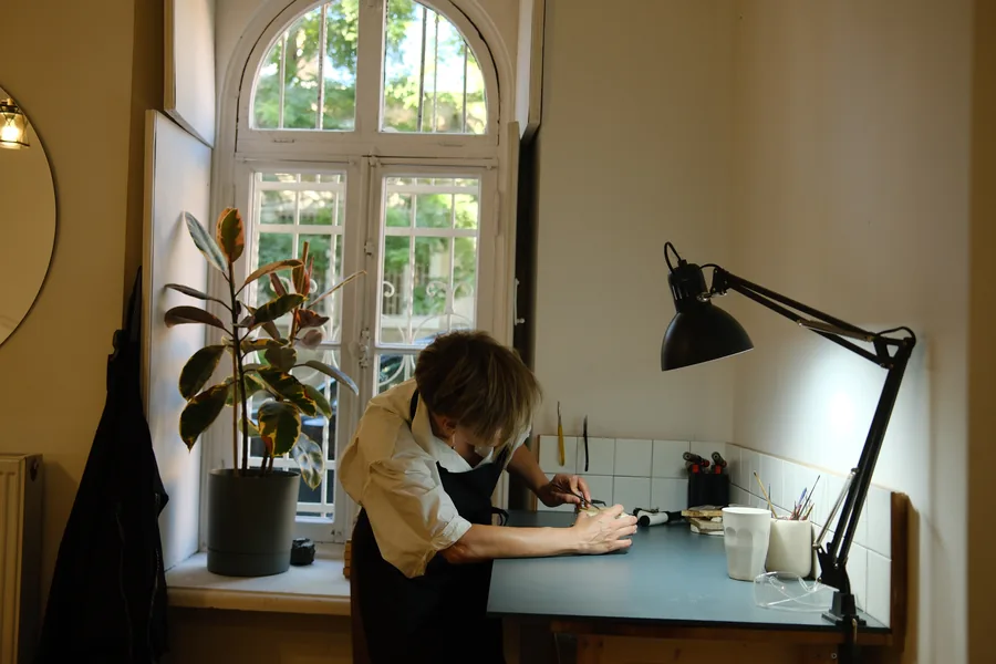 A student working at the bench under the arched window, a fig tree beside her