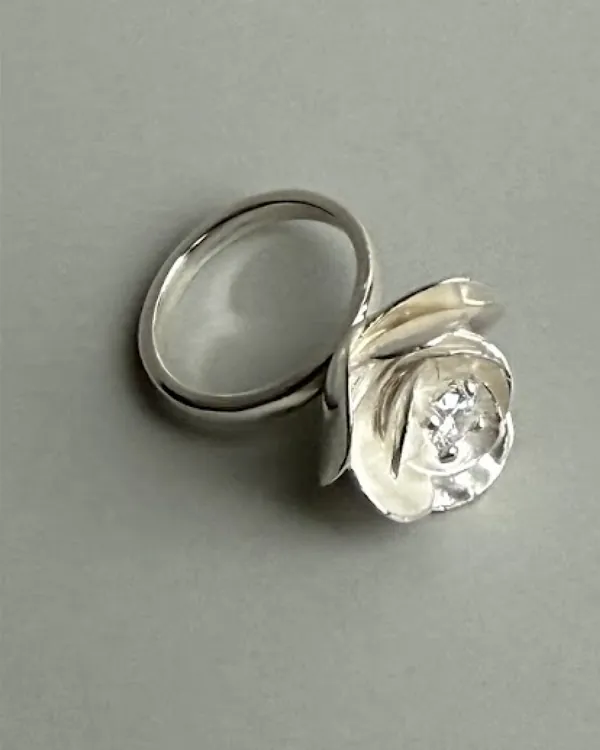 A silver ring with petals folded around a faceted stone