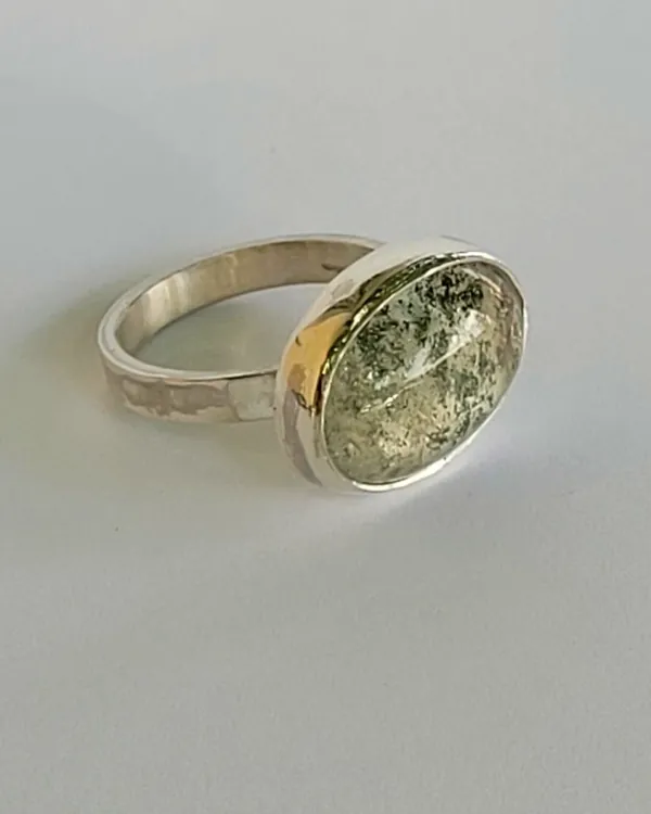 A hammered silver band with a large cabochon-cut stone in a bezel