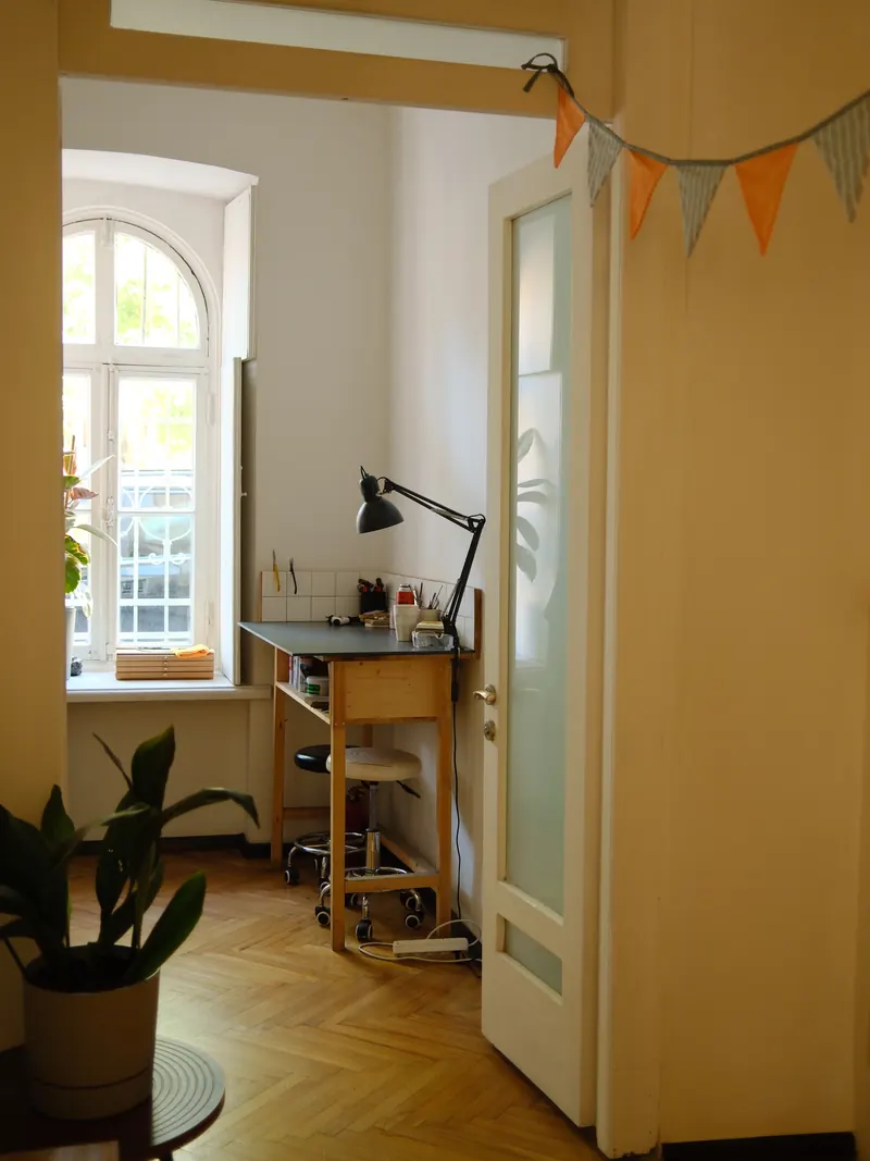 A jeweller's bench by an arched window: task lamp, stool and parquet floor