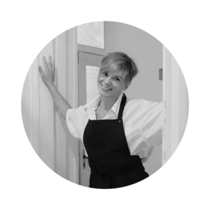 Emiliya Tumanova in a white shirt and black apron in the studio doorway