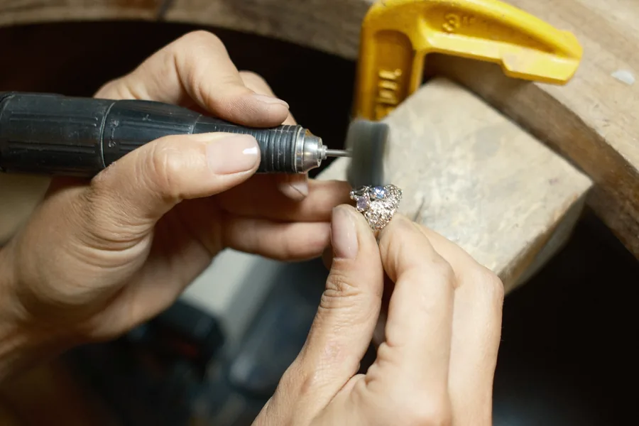 A jeweller's hands finishing a silver ring with a rotary tool at the bench